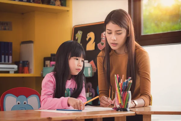 Lärare och elev ta hem arbete togather i förskolan — Stockfoto