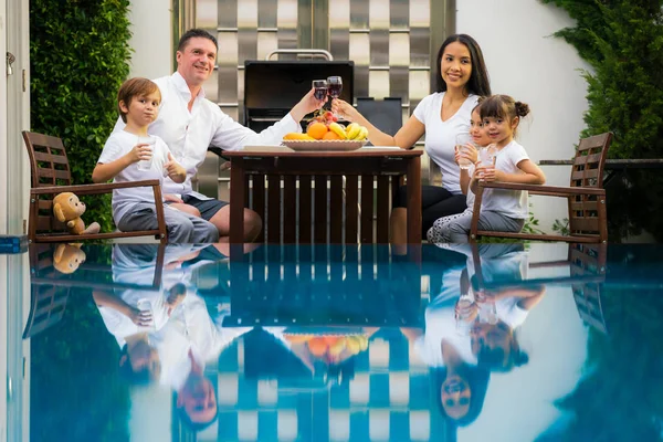 家族はプールで一緒に夕食を取る — ストック写真