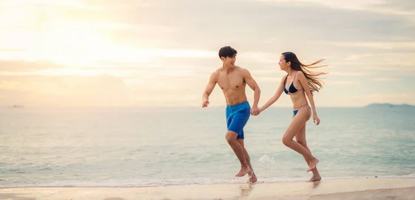 Asiatisch pärchen rennen tomeet auf die strand — Stockfoto