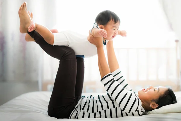 Asiatico madre giocare con il suo bambino su il letto — Foto Stock