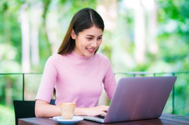 Asya Bayan bilgisayar not defteri ve içki kahve ile çalışma