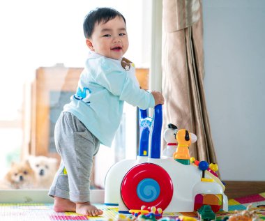 Asian baby training walking with walker toy clipart