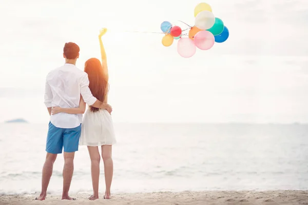 Pareja enamorada parada en la playa con bolloon — Foto de Stock