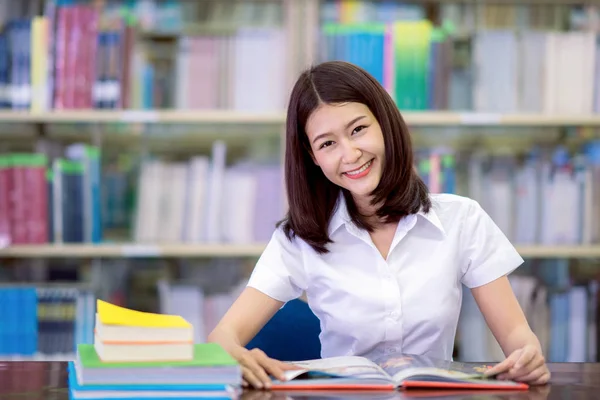 Aziatische Dame student glimlach en huiswerk in libraly — Stockfoto