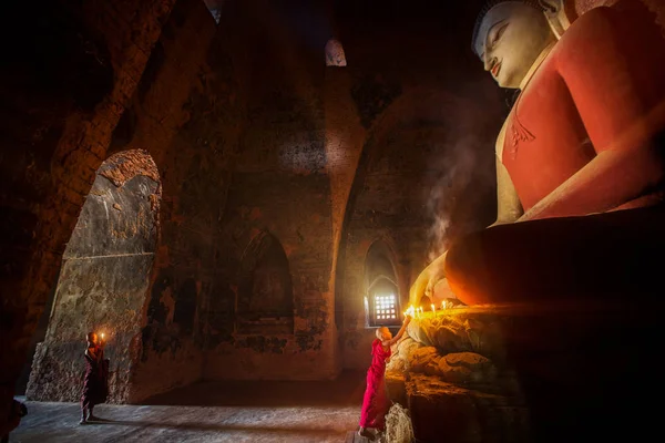 Monje en el casco antiguo de Bagan rezar una estatua de buda con vela — Foto de Stock