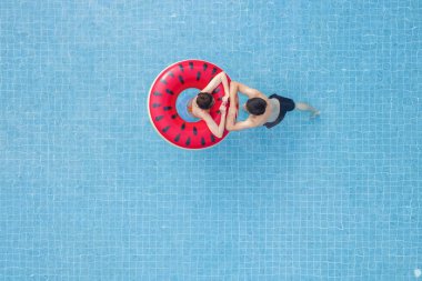 Asian couple in love in swimming pool on summer time