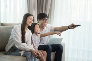 Asian family enjoy looking lcd tv on sofa in living room