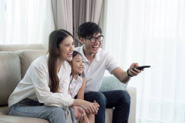 Asian family enjoy looking lcd tv on sofa in living room