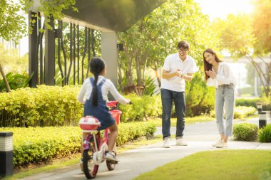 Daughter train to ride a bicycle from her moter and her father