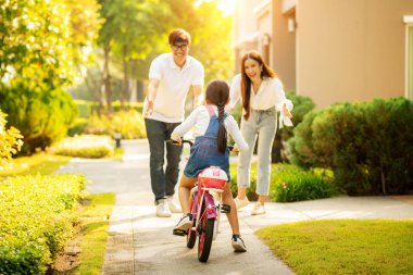 Daughter train to ride a bicycle from her moter and her father