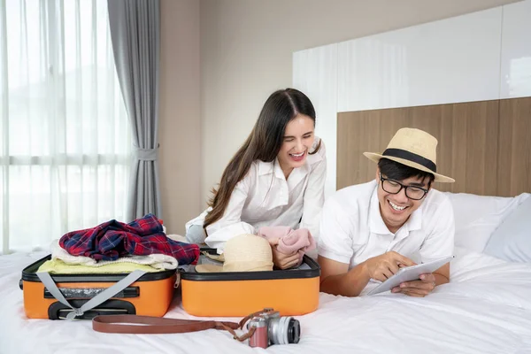 Mutlu Asyalı çift odadaki yatakta bavullarını topluyor.