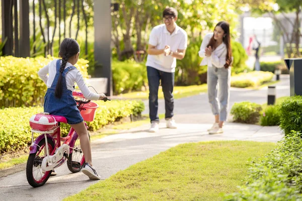 Bir kız babasından ve M 'sinden eğitim alarak bisiklete binmeye çalışır.