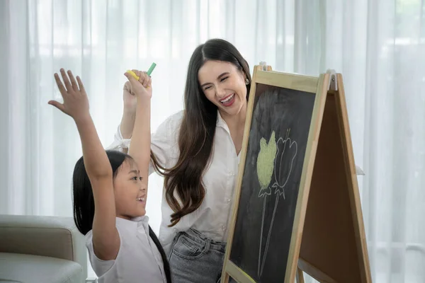 アジアの教師は、彼女の学生に自分のブラックボーに花を描くように教える — ストック写真