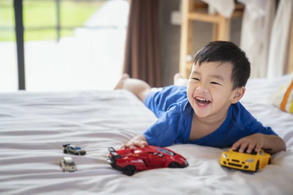 Asiatische junge Spaß und spielen ein Auto Spielzeug auf die Bett — Stockfoto