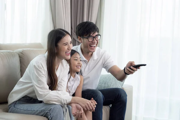 Ázsiai család élvez látszó lcd tv kanapén a nappaliban — Stock Fotó