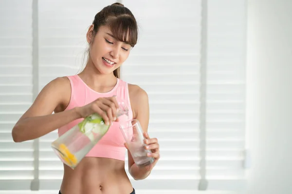 Menina asiática beber uma água de desintoxicação infundida após o exercício de acabamento em — Fotografia de Stock