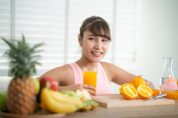 Aziatisch meisje maken een sinaasappelsap met de hand thuis na afloop e — Stockfoto