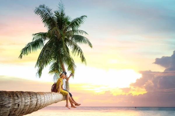 Asian couple sit on coconut tree — Stock Photo, Image