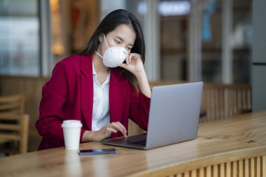 Asyalı kız Pm 2.5 ve Corona virüslerini önlemek için koruyucu maske kullanıyor veya Bangkok 'ta ofisinde kahve ile birlikte covic 19..