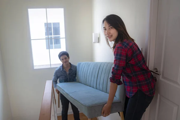 Asian husband and his wife lift a sofa to new house, this image can use for room, home and family concept