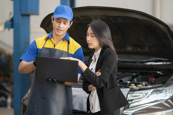 Mechanic showing customer the problem with car at the repair garage in car cervice center.