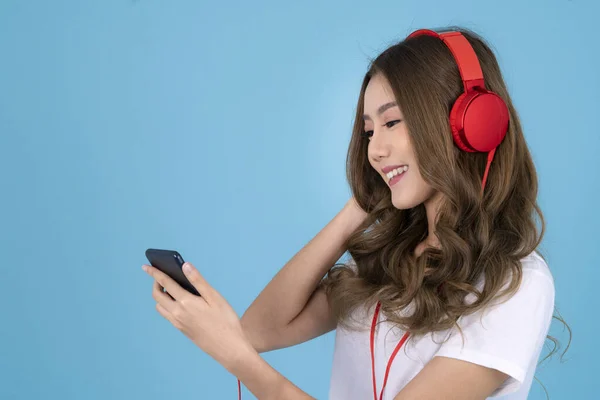 Kulaklıklı Asyalı Bir Kadın Mavi Izole Bir Arka Planda Müzik — Stok fotoğraf