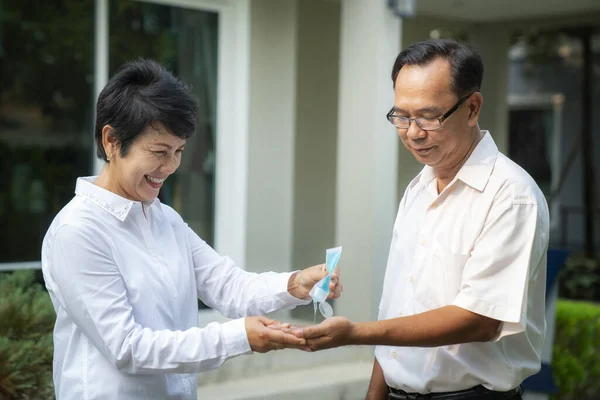 アジアの高齢者は 屋外ビジネスビルとCovid19ウイルスを防ぐために彼女の手を掃除アルコールゲルを使用します — ストック写真