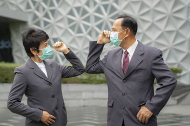Old asian business people greeting togather by new methode with mask for prevent covid 19, this image can use for covid-19, corona virus and shakehands concept. clipart