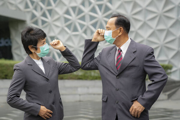 Old asian business people greeting togather by new methode with mask for prevent covid 19, this image can use for covid-19, corona virus and shakehands concept.