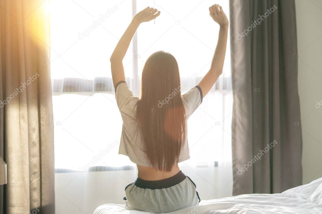 Asian Woman stretching in bed after wake up in bed room