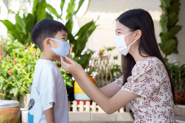 Asian mother wear a face mask to her son before go to market, this image can use for family, covid19 and health concept