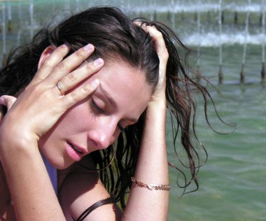 young woman cooling near the fountain in hot day           clipart