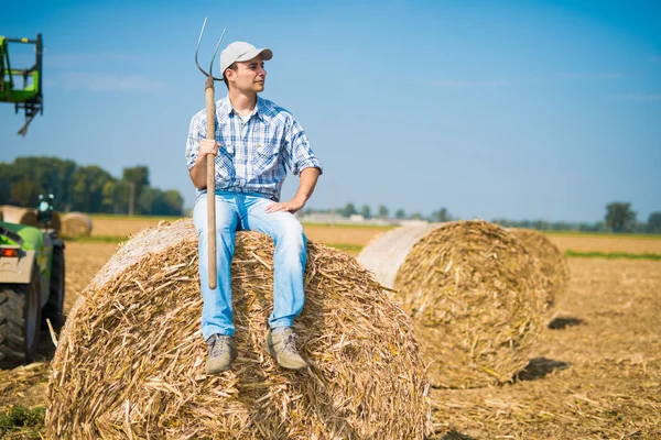 Farmer sitting on an hay bale — Stock Photo, Image