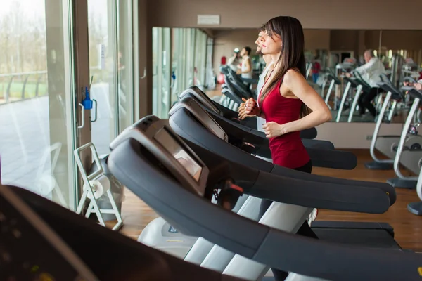 Mensen die werken op de loopband in de sportschool — Stockfoto