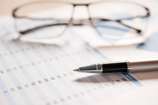 Pen and eyeglasses on financial documents — Stock Photo, Image