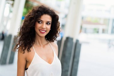 Gülümseyen bir kadın şehirde yürüyor