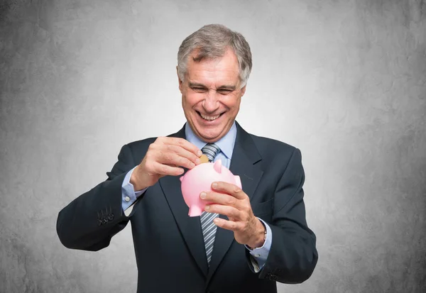 Man putting a coin in piggy bank — Stock Photo, Image