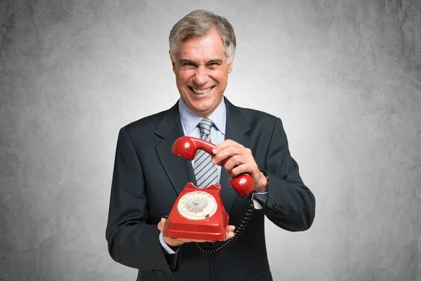 Mature businessman lifting vintage telephone — Stock Photo, Image