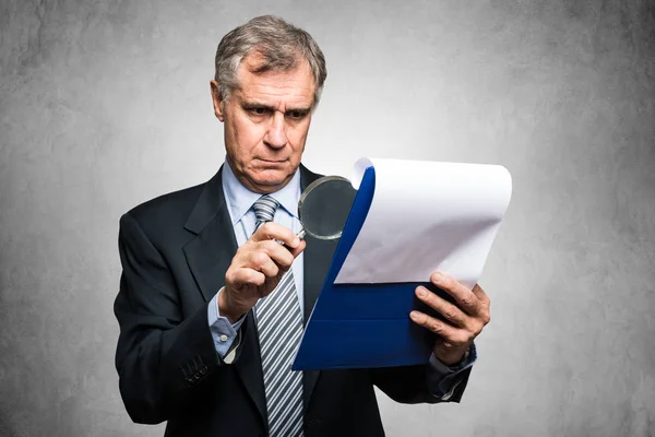 Businessman using magnifying lens — Stock Photo, Image