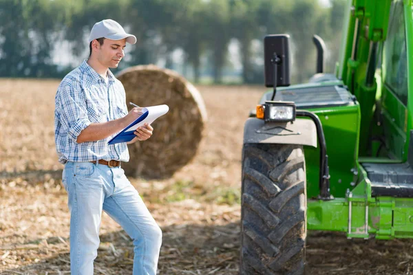 Farmer writing on a document on field — Stock Photo, Image