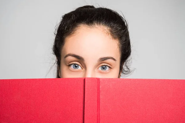 Menina adolescente olhando por trás do livro — Fotografia de Stock