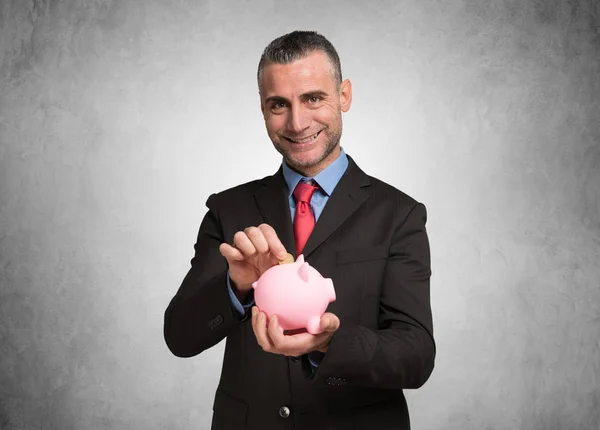 Homem colocando uma moeda no banco porquinho — Fotografia de Stock