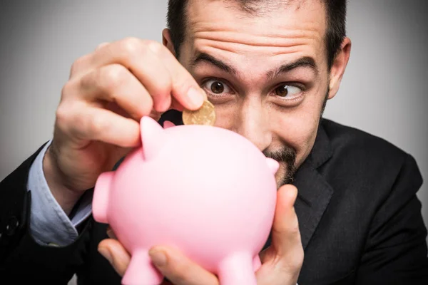 Empresário colocando dinheiro em banco porquinho — Fotografia de Stock