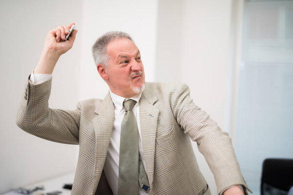 Злой бизнесмен выбрасывает телефон
