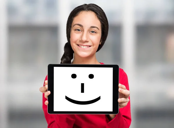 Flicka som håller en leende tablett — Stockfoto