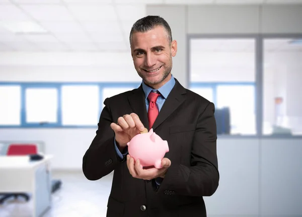 Homem colocando uma moeda em um banco porquinho — Fotografia de Stock