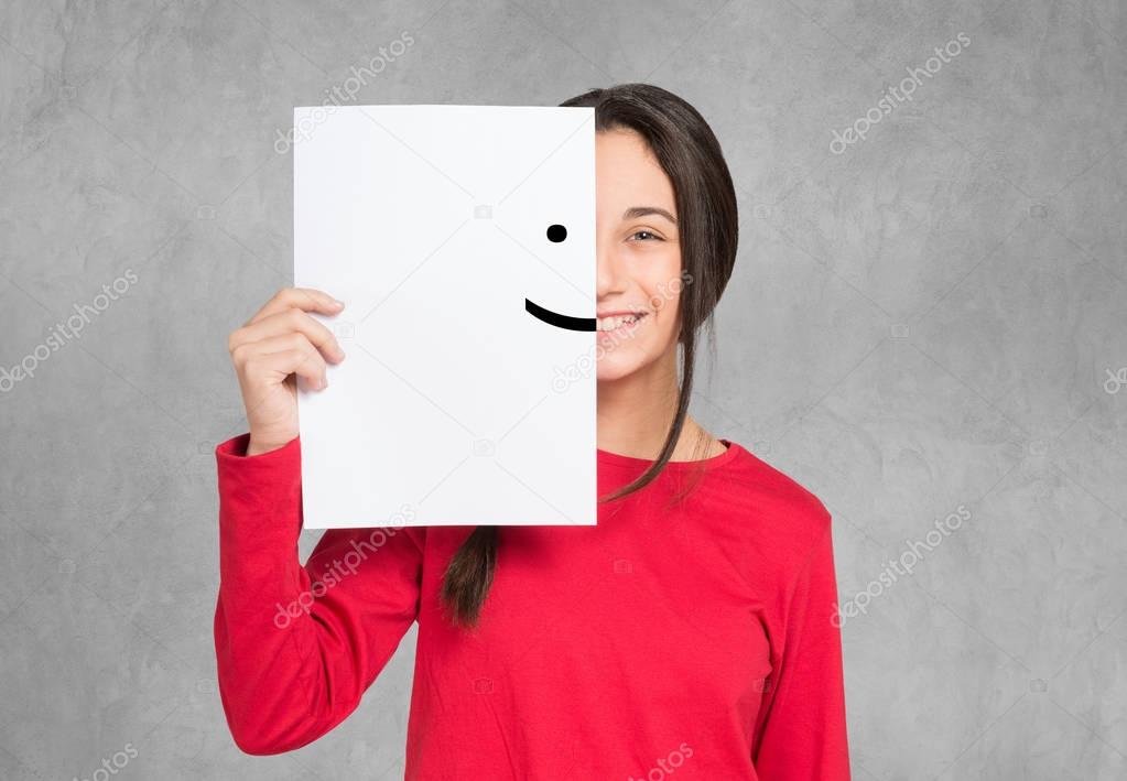 Teenager covering face with smiling emoticon