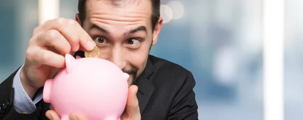 Empresário colocando dinheiro em banco porquinho — Fotografia de Stock