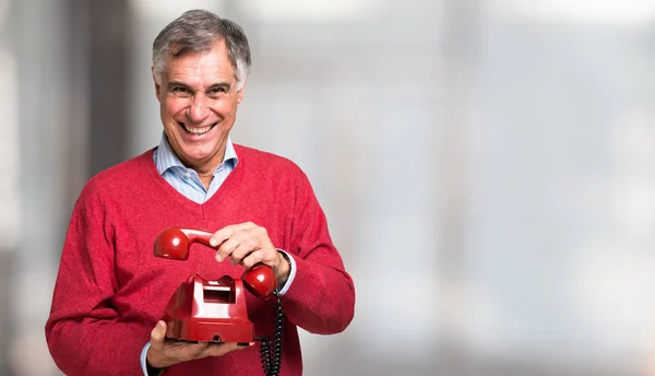 Человек с красным винтажным телефоном — стоковое фото