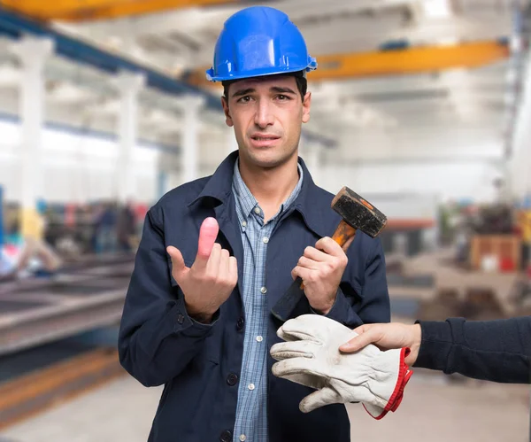 Werknemer lijdt aan een klap van de hamer op de vinger — Stockfoto